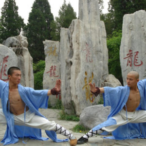 Monges Shaolin em posturas de Kung Fu na frente de estelas