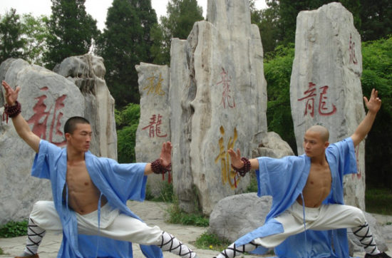 Monges Shaolin em posturas de Kung Fu na frente de estelas