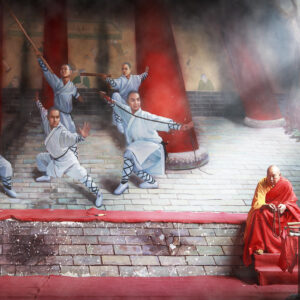Monge Shaolin idoso sentado diante de um mural de monges guerreiros