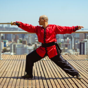 Homem com roupa tradicional chinesa furando o ar com uma espada de dois gumes